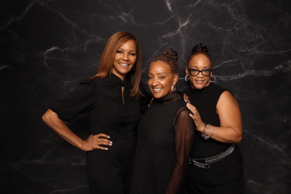 Three guests dressed in black posing against a marble backdrop