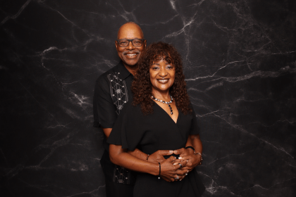 A smiling couple posing together against a marble backdrop